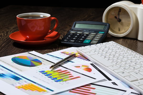 Workplace with keyboard cup of coffee and graphs