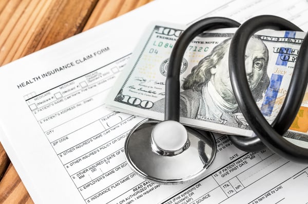Stethoscope wrapped around 100 dollar bill